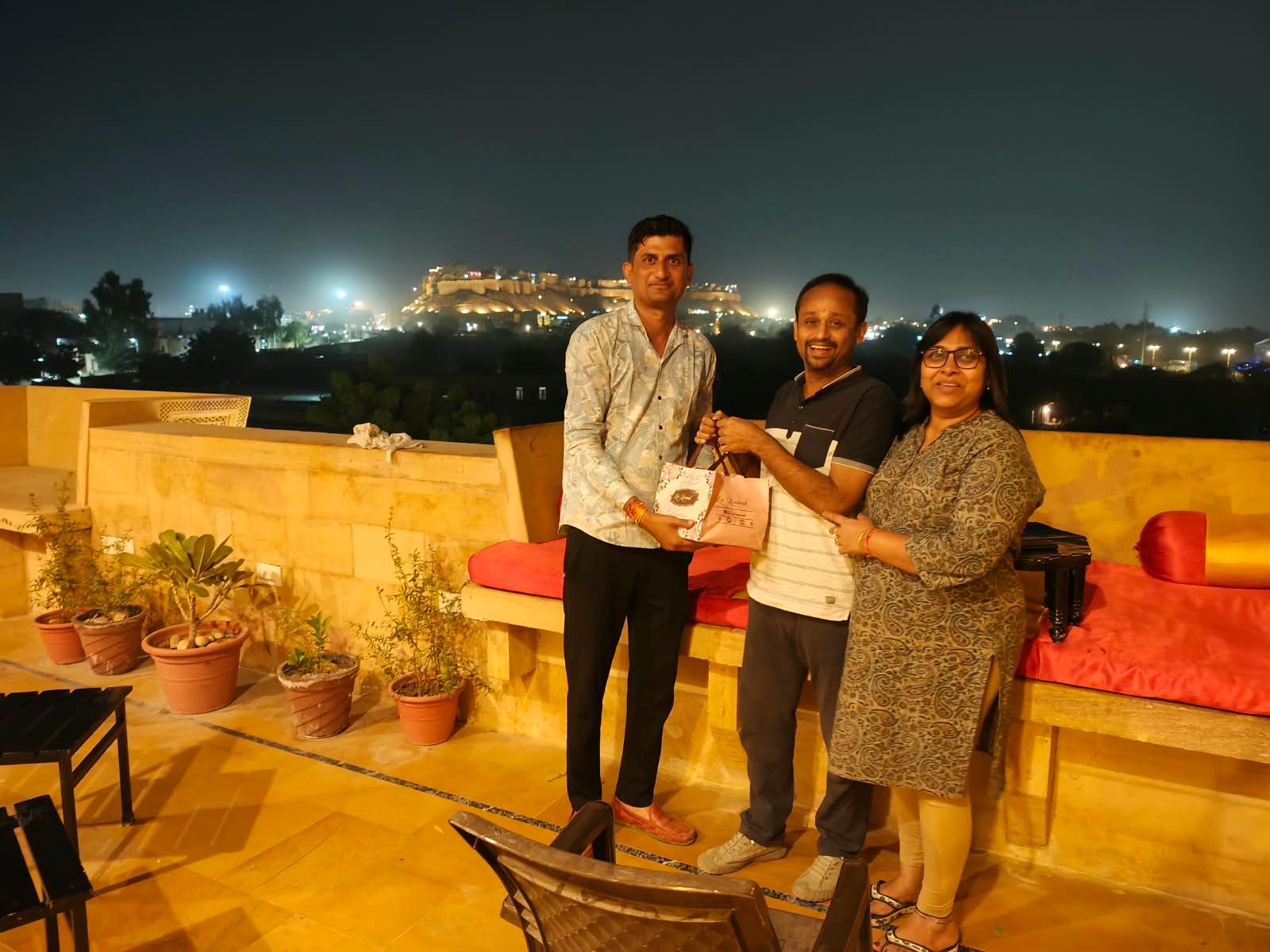 Guests on a rooftop with the fort lit at night